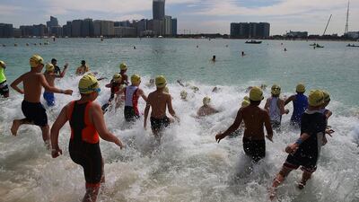 Juniors jump in to the water along the Abu Dhabi corniche for the start of the race.