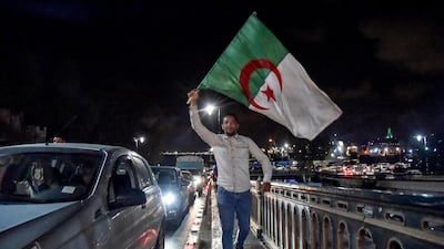 Algerian marches with a national flag during a demonstration in the centre of the capital Algiers on March 11, 2019, after President Abdelaziz Bouteflika announced his withdrawal from a bid to win another term in office and postponed an April 18 election, following weeks of protests against his candidacy. Bouteflika, in a message carried by national news agency APS, said the presidential poll would follow a national conference on political and constitutional reform to be drawn up by the end of 2019. / AFP / RYAD KRAMDI