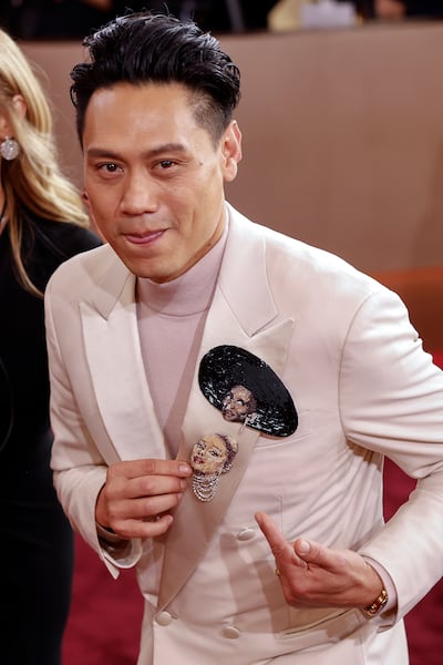 Wicked director Jon M Chu complements his beige tuxedo with bejewelled pins featuring his leading ladies. EPA