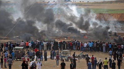 Palestinian protesters look at tear gas and smoke billowing from burning tyres, east of Gaza City, as Palestinians readied for protests over the inauguration of the US embassy following its controversial move to Jerusalem. Mohammed Abed / AFP