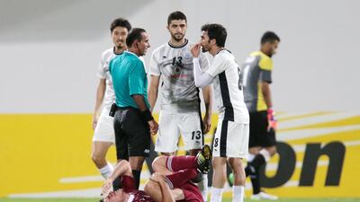 Al Wahda's Sebastian Tagliabue, centre, writhes in pain while Al Sadd's Ibrahim Majed (13) and Ali Asadalla Thaimn (8) speak to the referee. Christopher Pike / The National
