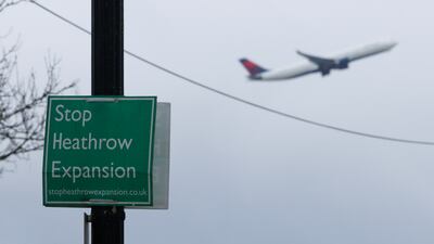 A plane takes off from Heathrow behind a sign against the proposed airport expansion. Getty Images