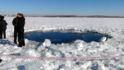Police stand near a six-metre hole in the ice of a frozen lake, the site of a meteorite impact, outside the town of Chebakul in the Chelyabinsk region. AFP