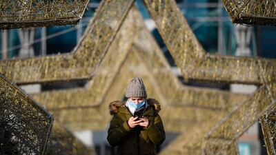 A woman wearing a face mask uses her smartphone while walking through a shopping centre in Moscow, Russia. AFP