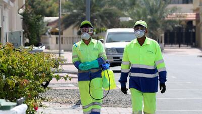 People disinfect bins in Jumeirah in response to the coronavrus as new visa renewals are introduced. Chris Whiteoak / The National