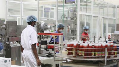 Workers oversee the tomato ketchup assembly line at the Chilly Willy manufacturing facility in Dubai, June 3, 2015.