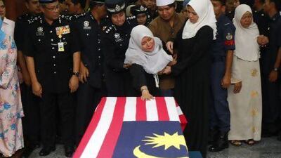 A family member cries while paying her last respects in front of the coffin of Superintendent Ibrahim Lebar, the Malaysian policeman who was killed in an ambush in Semporna. Malaysia sent hundreds of soldiers to a Borneo state on Monday to fight armed Filipino intruders. Lai Seng Sin / AP Photo