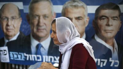 An Israeli arab woman serves beverages in front of an electoral poster at a poling station during Israel's parliamentary elections. AFP