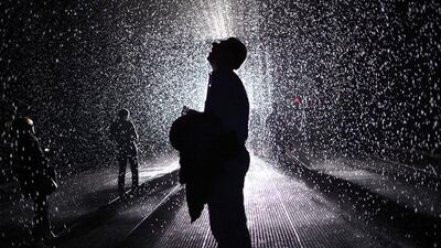 A visitor feels the water in "Rain Room" at The Museum of Modern Art in New York