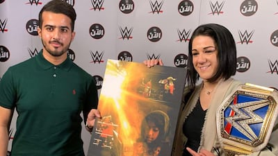 Saudi graphic designer Abdulmalik Ali Al-Muwizri, left, and WWE Superstar Bayley pose with Al-Muwizri's latest work. Instagram / Abdulmalik Ali Al-Muwizri