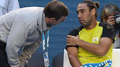 A courtside trainer checks on the shoulder of Marcos Baghdatis yesterday.