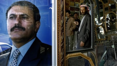 This file photo taken on January 24, 2010 shows the reflection of Yemenis in a mirror next to a picture of Yemeni ex-president Ali Abdullah Saleh in Sanaa. Saleh, who was slain by his former rebel allies, died aged 75 on December 4, 2017. Marwan Naamani / AFP