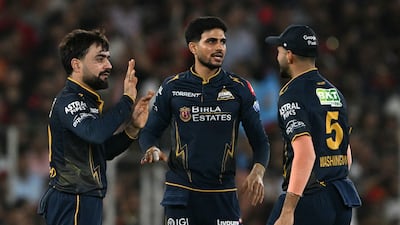 Gujarat Titans' Rashid Khan, left, took two wickets in one over against Royal Challengers Bengaluru. AFP