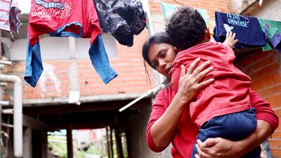 Francisca Cristiane carries her son Artur outside her home in the Brasilandia neighborhood in Sao Paulo, Brazil. She said she won't send her children to school because of Covid-19 fears.