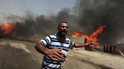 A Palestinian reacts in front of a fire which police said was caused by an Israeli tank shelling in the industrial area in the east of Gaza City. REUTERS/Ashraf Amrah