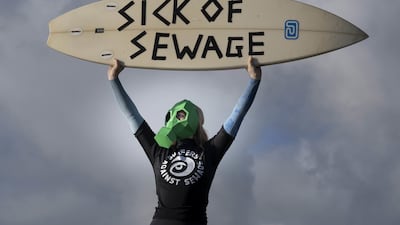 A representative from Surfers against Sewage protests against sewage discharges at an overflow pipe on Long Rock Beach in Penzance, Cornwall. PA