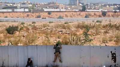 Rebel fighters observe the fighting near the main Muammar Qaddafi's compound in Bab Al-Aziziya district in Tripoli on Tuesday.