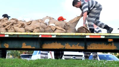 Trustees from the Brevard County Jail fill sandbags at the parking lot of Calvary Chapel for free distribution to residents. Florida Today via AP