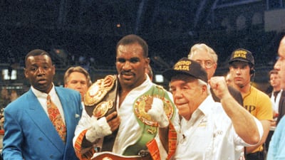 Evander Holyfield poses for a photo with his WBC, WBA, IBF Heavyweight championship Title belts after defeating George Foreman in a twelve round bout at the Trump Plaza Convention Center on April 19, 1991 in Atlantic City, New Jersey. Holyfield defeated Foreman in a unanimous decision and retained the undisputed heavyweight Title. Getty