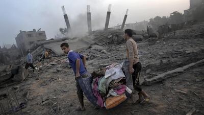 Palestinians try to salvage what they can of their belongings from the rubble of a house destroyed by an overnight Israeli air raid in Gaza City. Khalil Hamra / AP