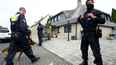 A German police officer and a sniffer dog enter the yard of a villa after a police raid in Leverkusen, Germany. Reuters