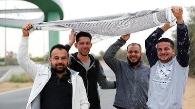 Workers try to stay dry from the rain near Town Square, Dubai. Chris Whiteoak / The National