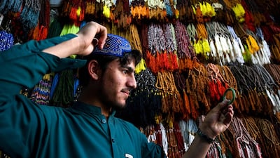 A Pakistani Muslim poses as he tries on a traditional prayer cap at a shop in Rawalpindi ahead of the start of Ramadan. AFP