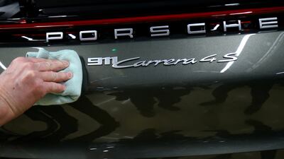 An employee fixes a Porsche 911 Carrera 4S label, at the car maker's factory in Germany. Reuters