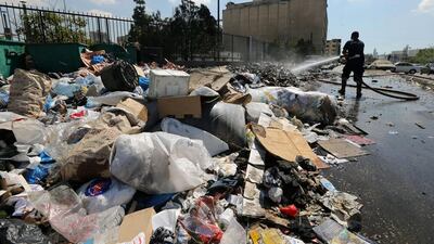 A firefighter sprays water on a rubbish pile that took fire on a street in Beirut on August 28. AFP Photo