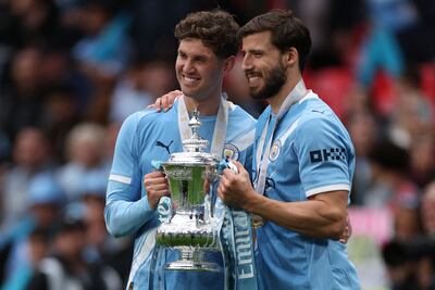 Manchester City's John Stones, left, and Ruben Dias with the 2026 FA Cup trophy. AFP