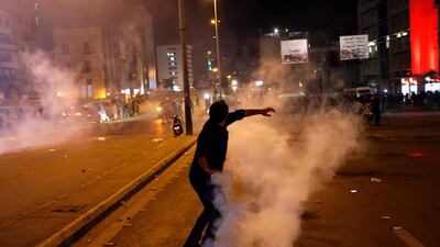 A protester throws back a tear gas canister that was fired towards them by Lebanese riot police during an anti-government protest in Beirut, Lebanon. AP Photo