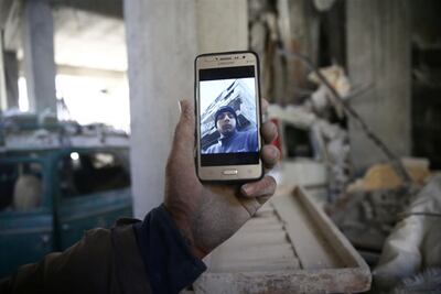 Abu Mohammed Alaya holds a mobile phone with his son's picture on the screen in Douma, Syria on March 2, 2018. Bassam Khabieh / Reuters