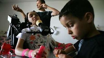 Maria Aman, who is paralysed from her neck down, sits in her hospital room with her younger brother Moman and her father Hamdi, in Jerusalem.