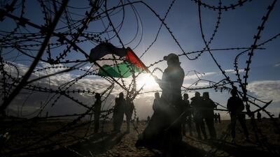 Palestinian protesters wave a national flag near concertina wire at the Israel-Gaza border, east of Rafah in the southern Gaza Strip. AFP