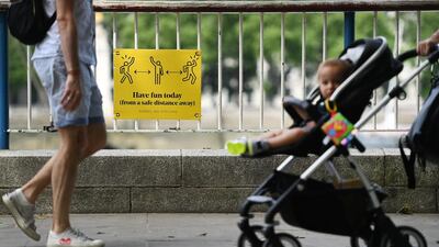 Pedestrians pass a social-distancing sign along the Southbank in London. EPA