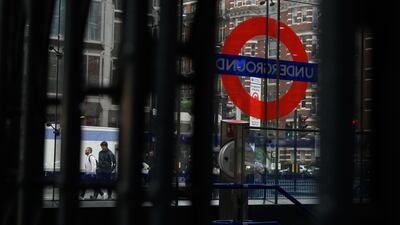 Commuters walk past a locked Tube station entrance in London. Getty Images
