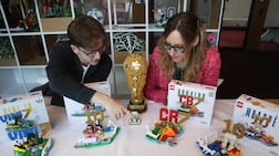 Model designer Freddy Charter, left, and design master Beatrice Amoretti display the Lego Editions sets of footballers Vinicius Jr, Lionel Messi, Cristiano Ronaldo and Kylian Mbappe. Reuters