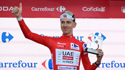 Tadej Pogacar celebrates on the podium wearing the overall leader's red jersey after winning the first stage of the Vuelta a Espana. AFP