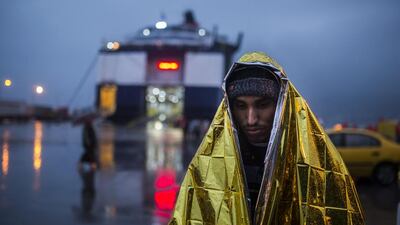 A man wrapped in a thermal blanket waits to get on board a ferry bound to Piraeus at the port of Mytilene, on the Greek island of Lesbos. (AP / Santi Palacios)