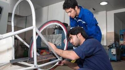 Driver Khalifa Ali Ahmad Awadh, kneeling, and the lead builder Humaid Al Araidi, the lead builder, work on the vehicle that the HCT Dubai are entering for the eco-friendly car competition. Courtesy of HCT