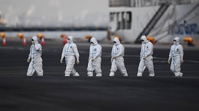 People wearing protective suits walk from the Diamond Princess cruise ship, with around 3,600 people quarantined onboard due to fears of the new coronavirus, at the Daikoku Pier Cruise Terminal in Yokohama port. AFP