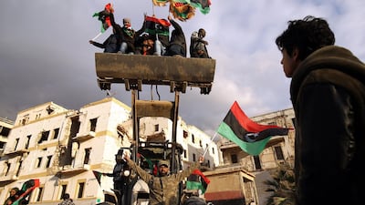 Libyan men on a bulldozer wave the national flag as they gather to mark the eighth anniversary of the uprising in Libya's second city of Benghazi. AFP