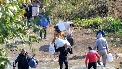 TOPSHOT - Families of Syria's Alawite minority cross the Nahr al-Kabir river, forming the border between Syria's western Latakia province and northern Lebanon in the Hekr al-Daher area on March 11, 2025, to enter Lebanon while fleeing from sectarian violence in their heartland along Syria's Mediterranean coast. (Photo by Fathi AL-MASRI / AFP)