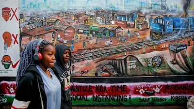 People walk past an informational mural with messages in English and Swahili warning about the dangers of the new coronavirus and how to prevent transmission, painted by youth artists from the Uweza Foundation, in the Kibera slum, or informal settlement, of Nairobi, Kenya. AP