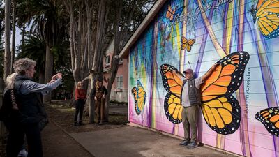 Tourists pose near the Monarch Grove Sanctuary in Pacific Grove, California. AP