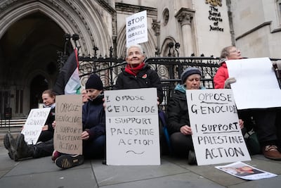 Protesters hold placards outside the High Court. PA