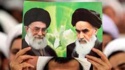A cleric holds a picture of the Islamic republic's supreme leader, Ayatollah Ali Khamenei, left, and its late founder, Ayatollah Ruhollah Khomenini in Tehran.
