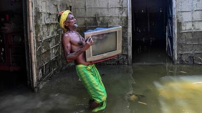 A man carries his belongings from his partially submerged house in India's Assam state. AFP