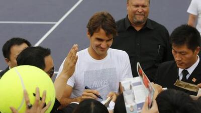 Roger Federer is flanked by security guards as he signs autographs for fans at the Shanghai Masters