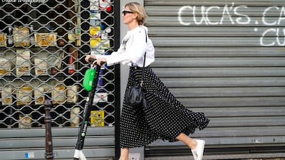 PARIS, FRANCE - JULY 03: A woman wears a white shirt, sunglasses, a black and white polka dots skirt, a black bag, white sneakers, and is riding electric a scooter Lime-S from the bike sharing service company "Lime", outside Valentino, during Paris Fashion Week -Haute Couture Fall/Winter 2019/2020, on July 03, 2019 in Paris, France. (Photo by Edward Berthelot/Getty Images)